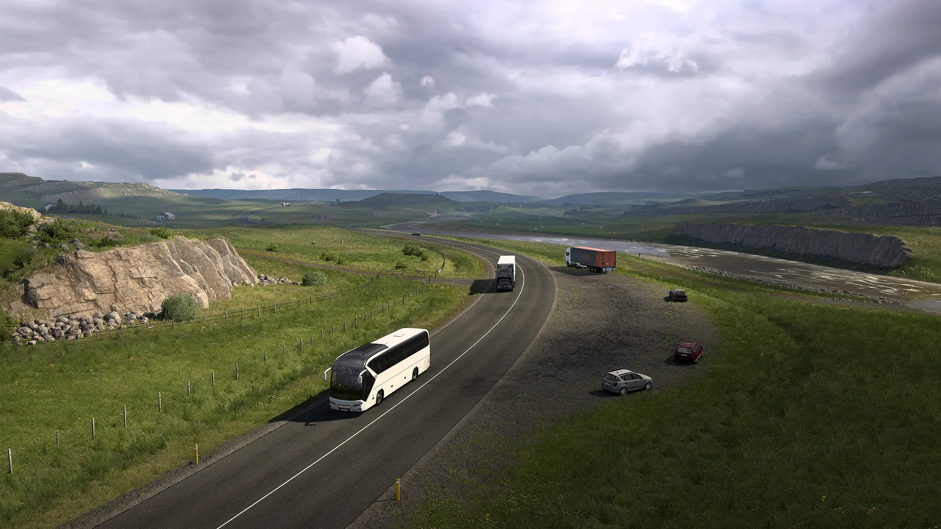 A coach and trucks on a two-lane road through green Icelandic countryside